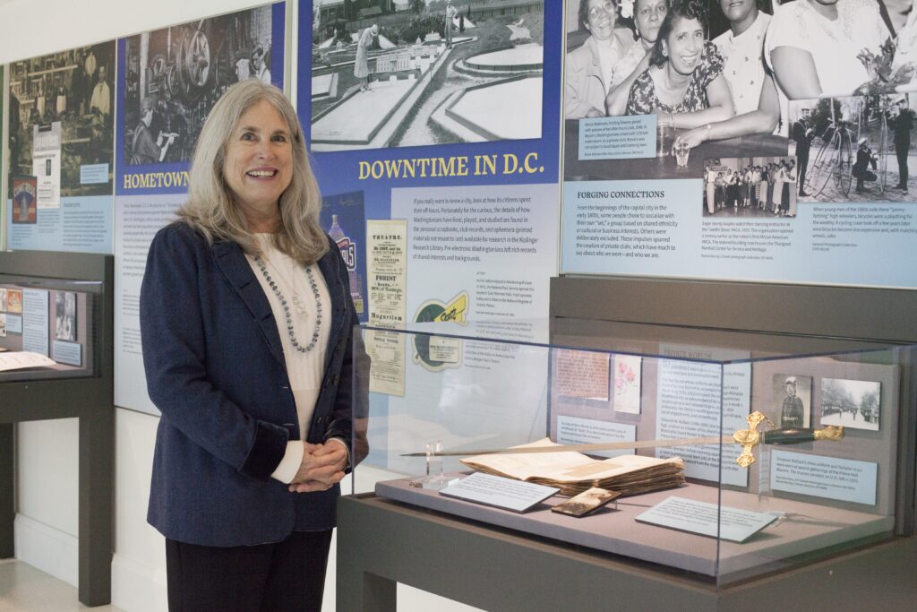 Julie Koczela stands beside an exhibit case inside the Hall of History exhibit.