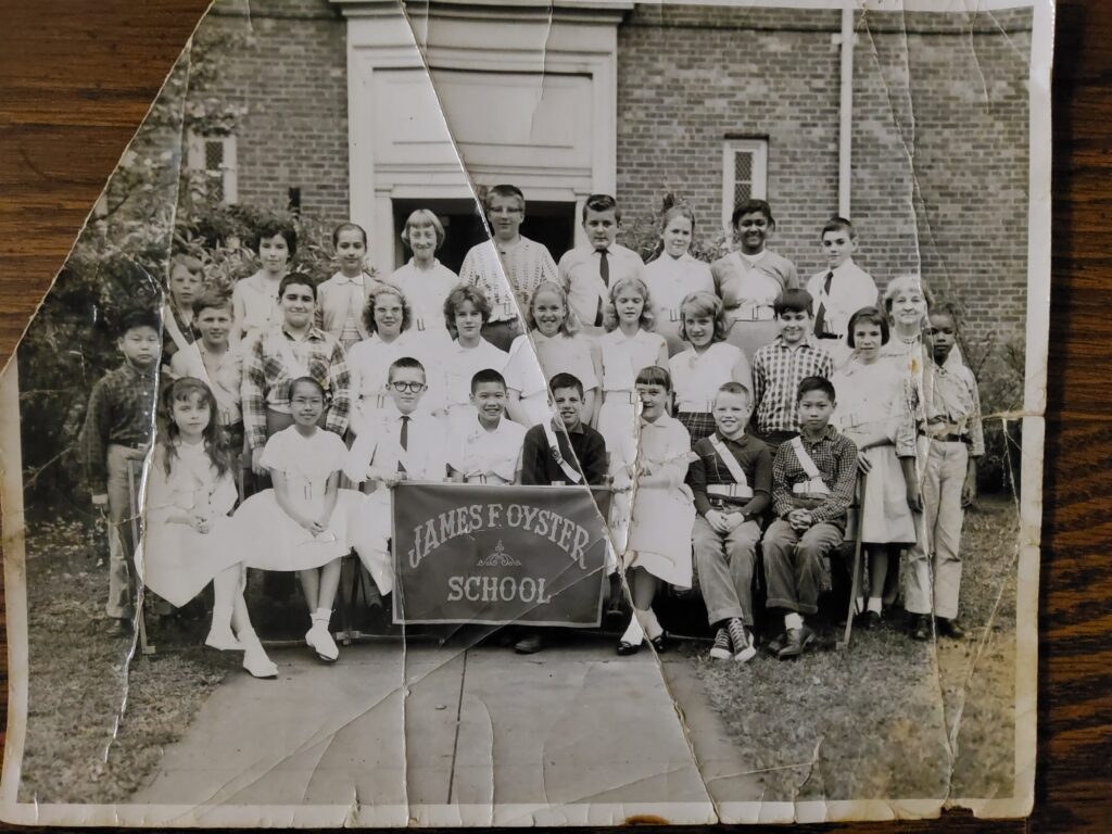 A creased black and white photo shows the James F. Oyster School Safety Patrol in 1961. Fifth grader Earl P. Williams, Jr. is in the second row at the far right.