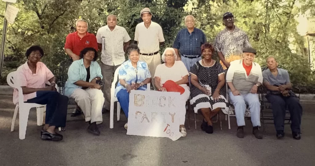 An early 2000s photograph showing reunion of AHRA members and neighbors who had established the Annual Block Party. The green space serves as a backdrop.